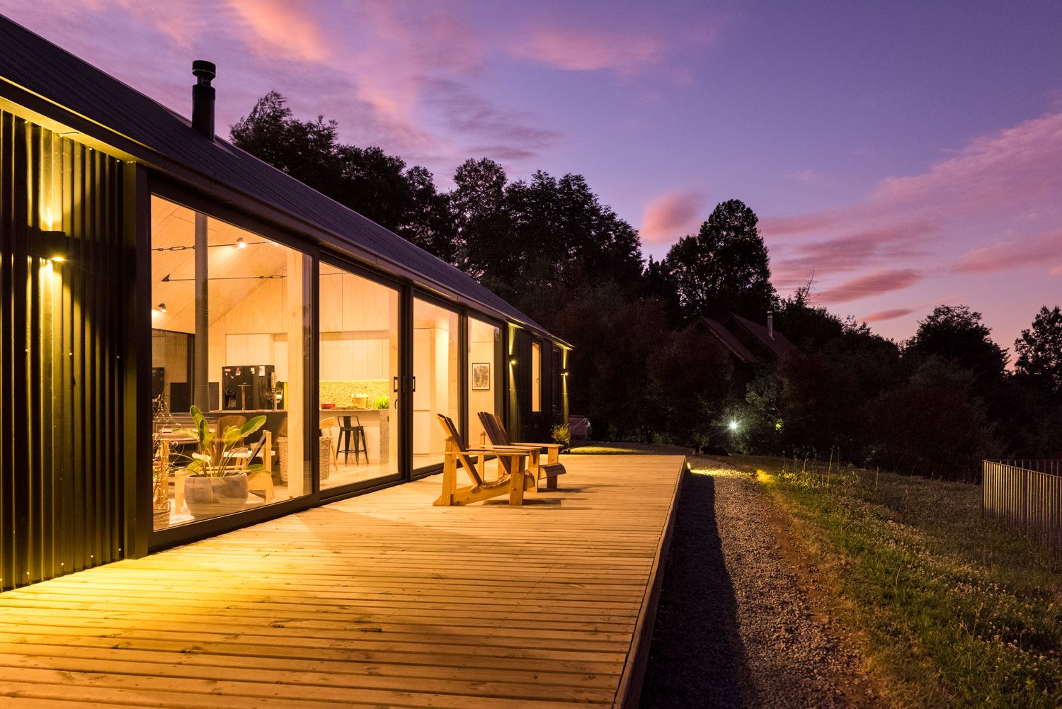 Casa Nordhaus negra con terraza de madera iluminada al atardecer