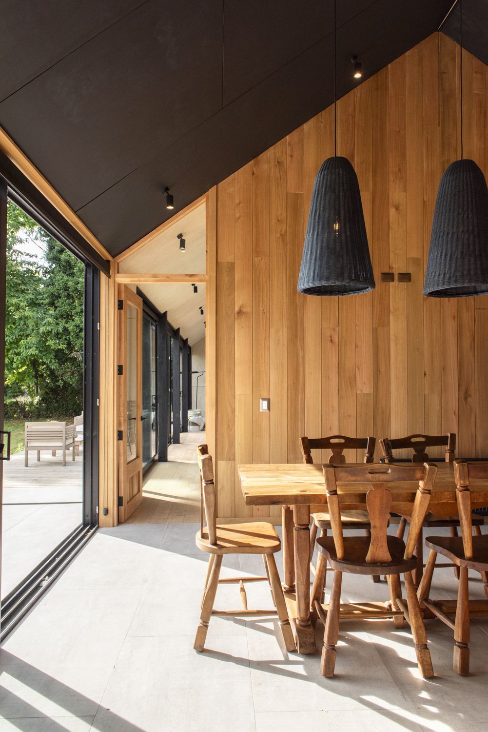 Interior de casa Nordhaus con cielo de madera, comedor y lámparas negras