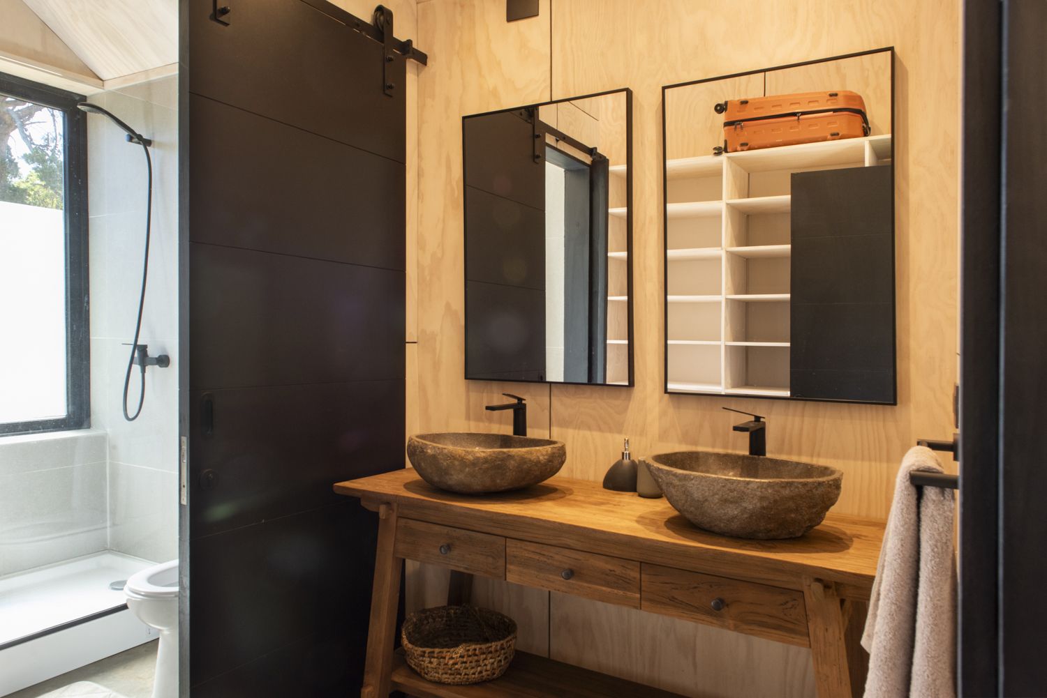 Baño con muebles de madera y lavamanos de piedra